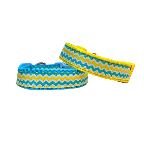 Dog collars featuring a blue, yellow and white wave themed ribbon. The collars have blue and yellow webbing and buckles.