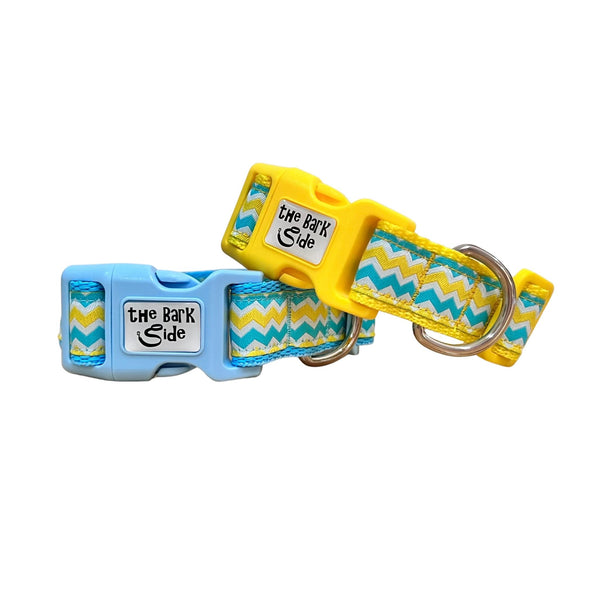 Dog collars featuring a blue, yellow and white wave themed ribbon. The collars have blue and yellow webbing and buckles.