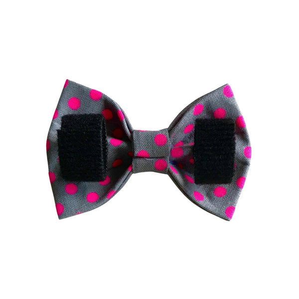 Reverse side of a bow tie. Grey fabric with neon pink spots. Two velcro straps to attach the bow tie to the collar.